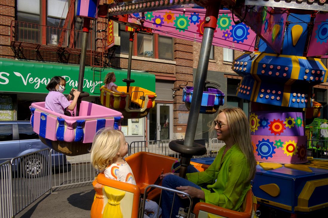 A mother and daughter play at a carnival ride on Hester Street.
